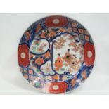 An early 20th century Japanese porcelain Imari charger, the centre decorated with three ladies in