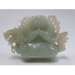 A Chinese celadon green jade carving depicting a portly immortal upon the back of a mythical beast