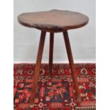 An early 18th century elm tripod table, the top of broken circular shape raised on three tapering