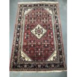 A Caucasian hand knotted wool rug with central lozenge medallion with foliate design surrounded by