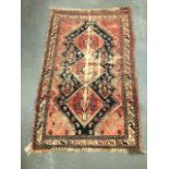 A middle eastern hand knotted wool rug with a row of three lozenge medallions amongst floral