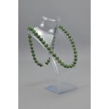 A CHINESE JADE BEAD NECKLACE WITH WHITE METAL CLAS