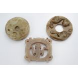 Two Chinese Bi disc form jade pendants each carved with dragons. Together with one other pendant