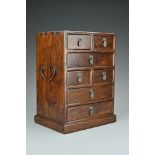 A Chinese hardwood apprentice cabinet. Of rectangular form with seven drawers, two brass handles and