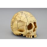 A Japanese ivory Netsuke in the form of a skull. The skull with incised decoration of a spiders