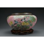 A Japanese cloisonné enamel jardiniere with birds and flowers on a pink ground. Standing on a carved