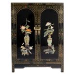 A Chinoiserie black lacquer cabinet with raised and painted decorations, including a brass lock