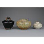 Three Southeast Asian pottery jars. One covered in a black and russet glaze, the others in greyish-