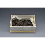 A box of loose Chinese compressed tea pieces. Each piece with with impressed decoration of