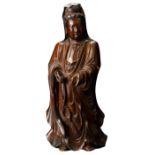 A Chinese 17/18th Century carved boxwood figure of Guanyin. The figure standing with downcast eyes