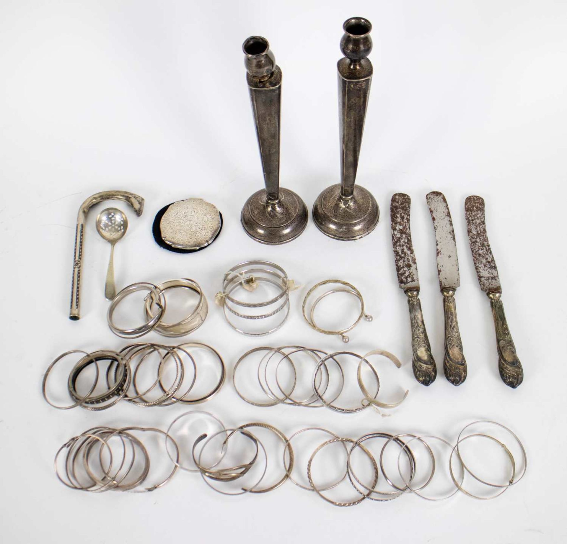 Lot with a pair of silver candlesticks, knifes and bracelets