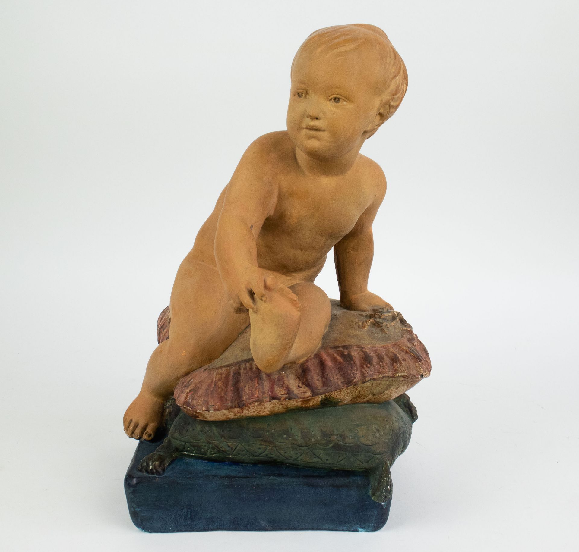 A patinated plaster sculpture of a child on a pillow