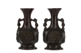 AN EARLY 20TH CENTURY PAIR OF JAPANESE BRONZE TWIN HANDLED VASES