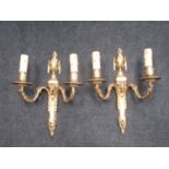 A pair of Louis XVI style brass two branch Wall Sconces with urn finials and ram's head masks,