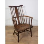 A primitive Windsor Armchair in elm, oak etc with shaped solid splat and turned spindles, dished