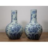 A large pair of Chinese blue and white Vases, bottle shaped and decorated dragons amongst foliage in