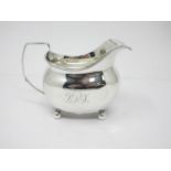 A George III silver boat shape Milk Jug with reeded rim, engraved initials, on ball feet, London