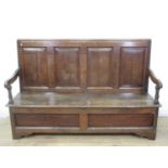 An antique oak Settle with fielded panelled back, shaped arms and replacement panels to the base,