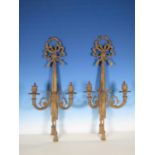 A pair of gilt metal two branch Wall Lights with ribbon finials, the back plates in the form of