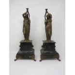 A pair of bronze female Figures, holding torches on black slate bases with bronze paw supports,