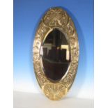 A small Arts and Crafts oval brass Wall Mirror with embossed design of butterflies and scrolls
