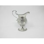 An Edward VII silver helmet shape Cream Jug with floral embossing on pedestal base, Chester 1905