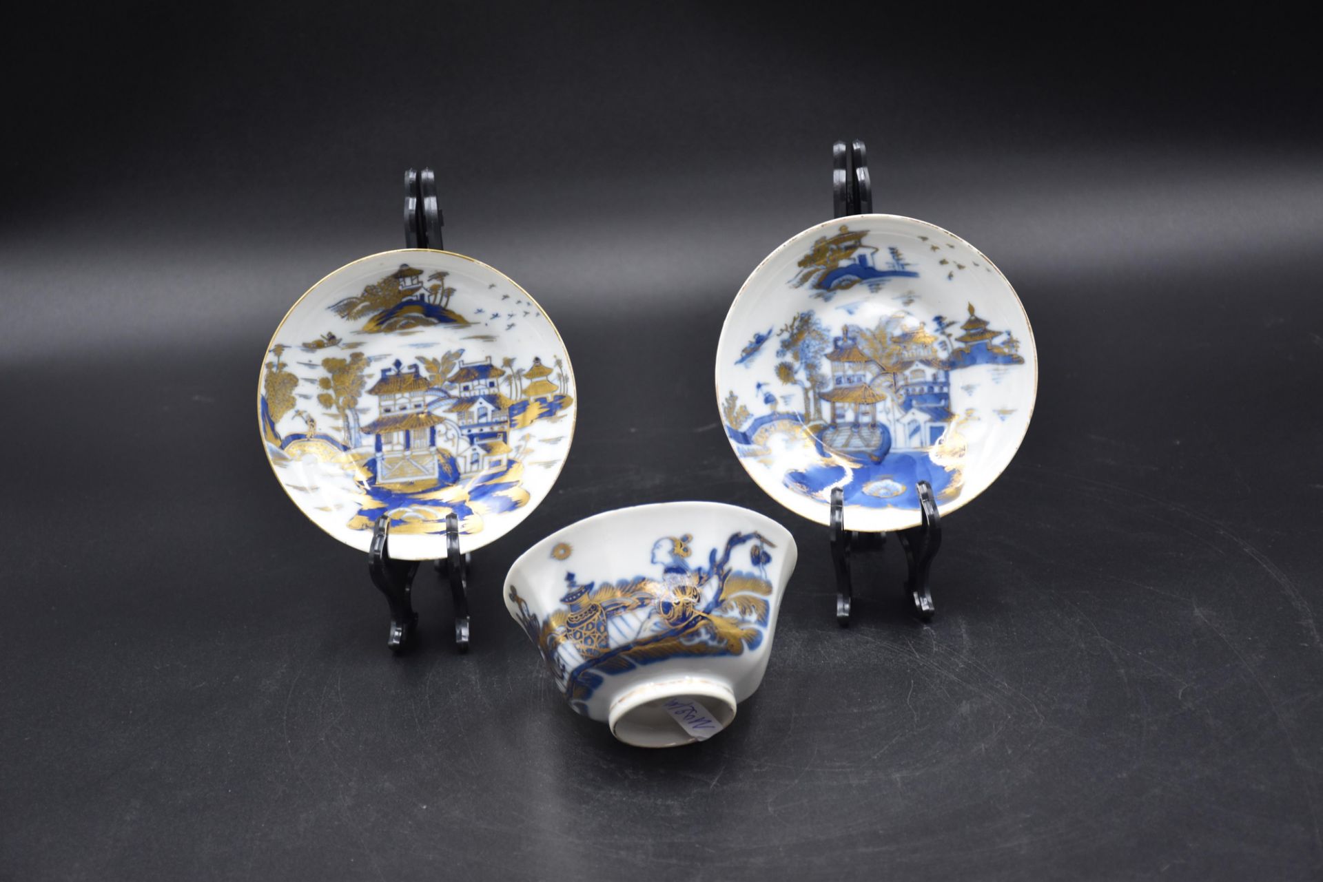 Bowl and two saucers in Chinese porcelain with blue and gold decoration of pagodas and characters.