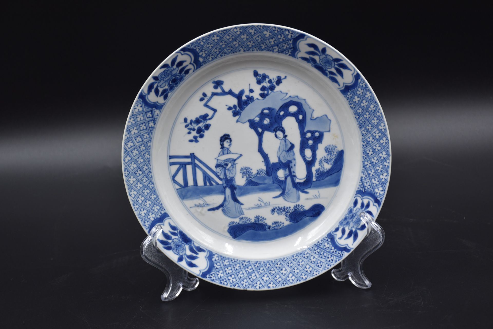 Chinese porcelain plate with white/blue decoration of two elegant women in a landscape.