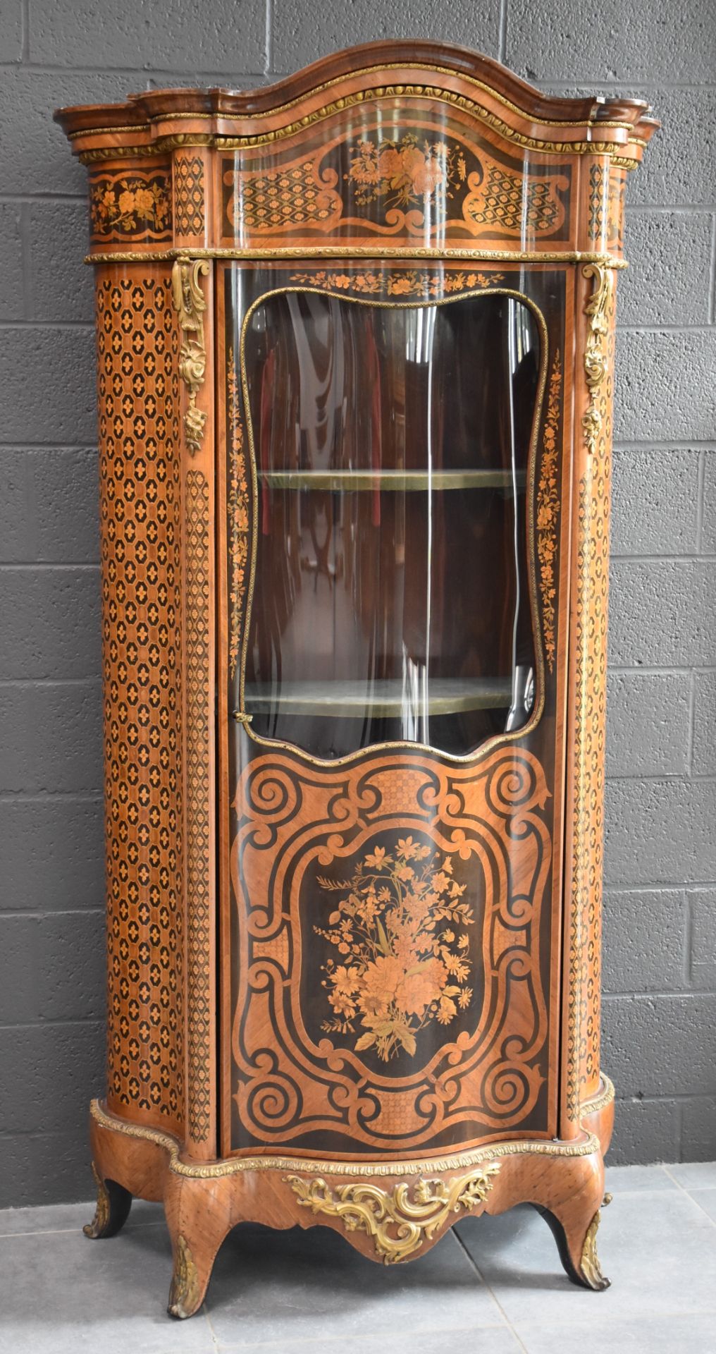 Curved display case in veneer and beautiful floral marquetry. Beautiful ornamentation of gilded