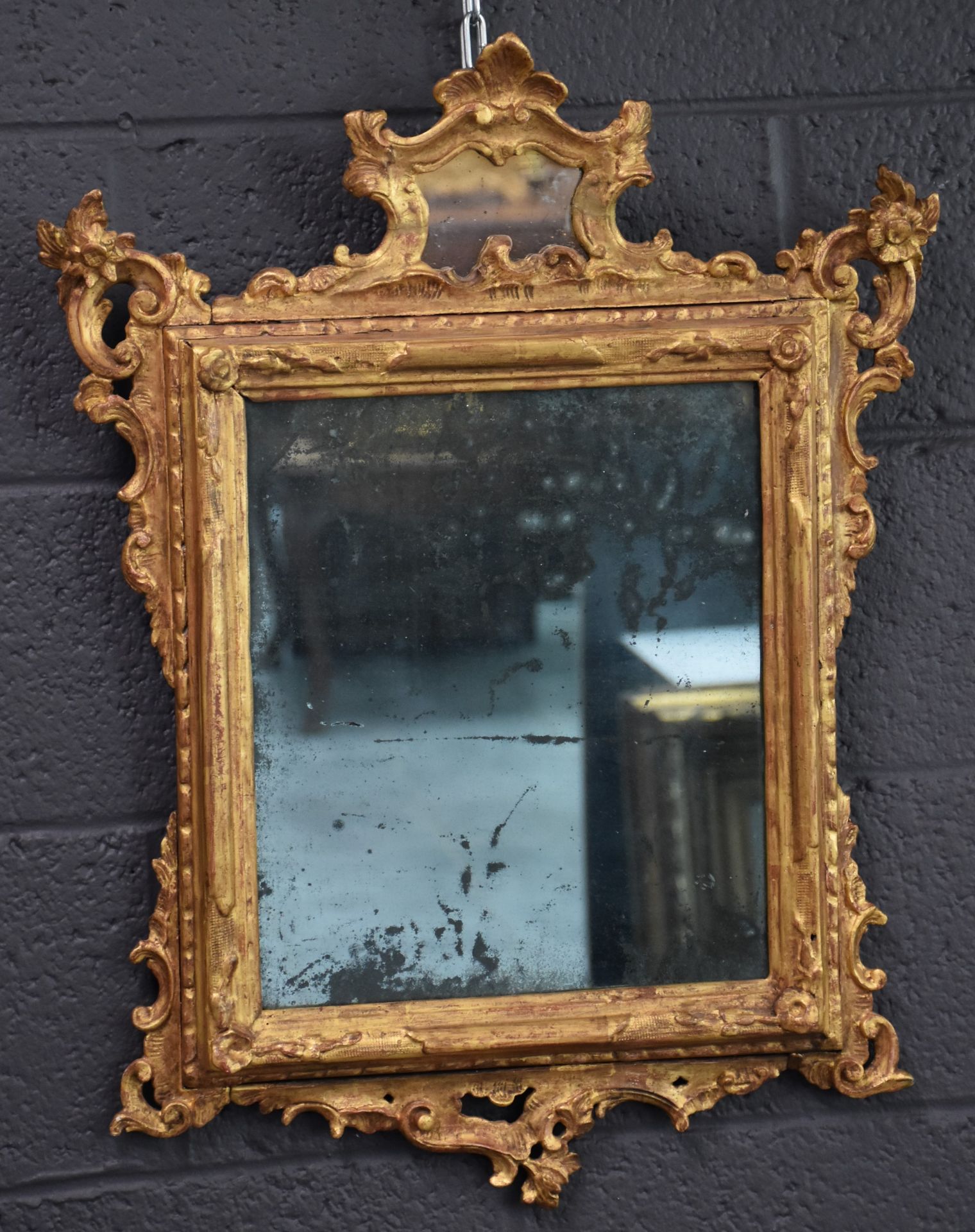 A carved and gilded wood mirror from the 18th century. Later gilding. Height : 68 cm.