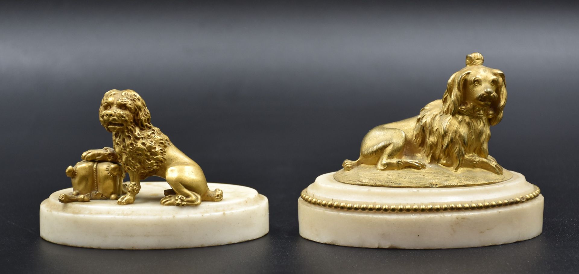 A pair of gilt bronze dogs on white marble bases. Late 18th century. One dog to be reattached. Total