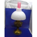 A brass based oil lamp with pink chimney 55cm tall