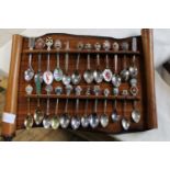 A collection of souvenir spoons on a wooden rack