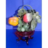 A quality Chinese hard stone Jadeite fruit basket on a wooden stand
