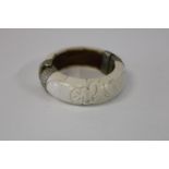 A antique Chinese hand carved ivory bangle with white metal clasps
