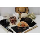 A box of assorted hats & hand fans etc