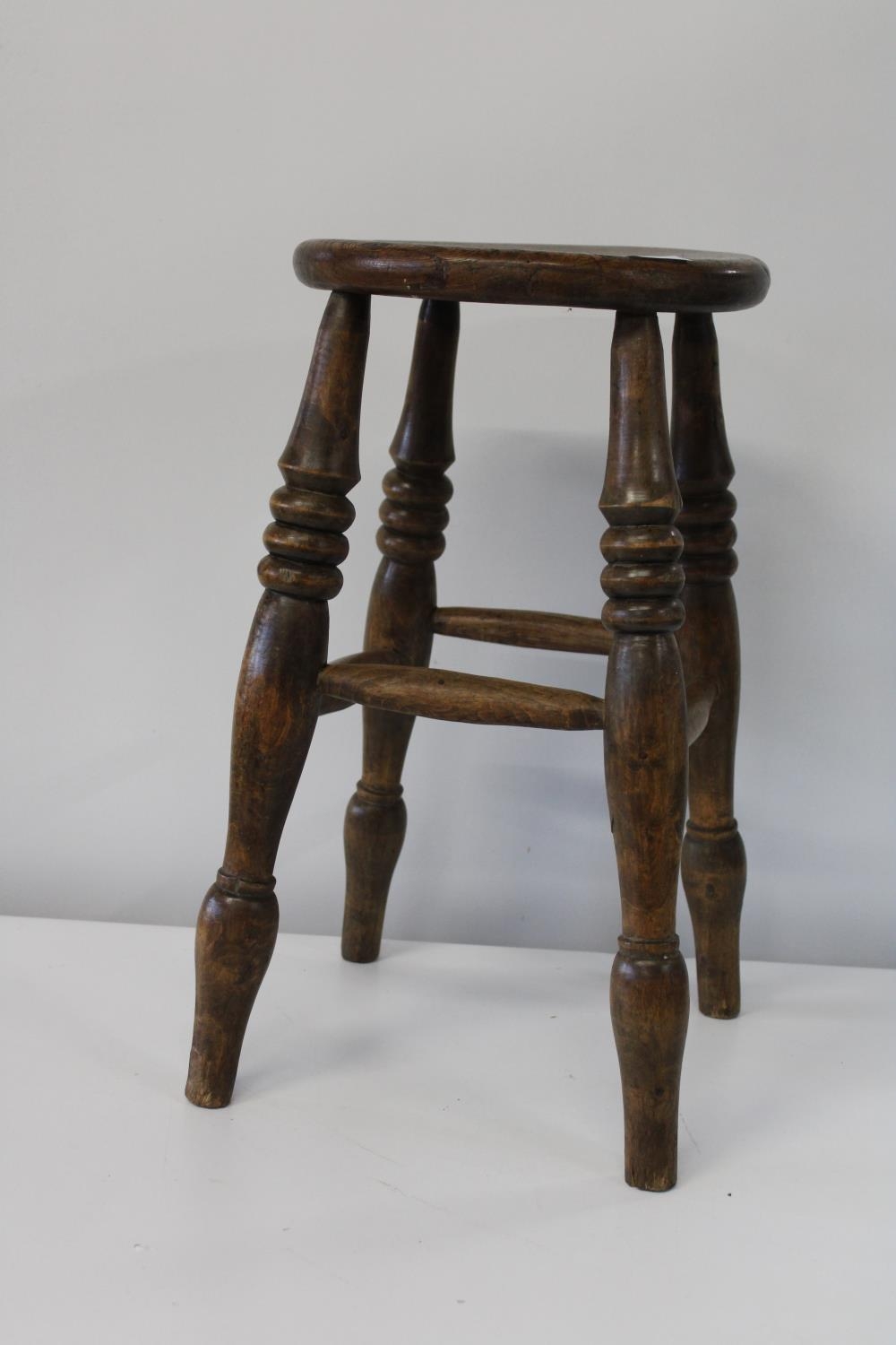 An antique Elm four legged stool. Height 53cm