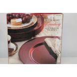 A boxed set of eight cranberry coloured charger plates