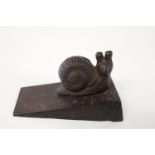 An antique cast iron door wedge in the shape of a snail