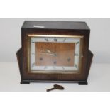 An Art Deco period wooden cased mantle clock with key. (needs attention)