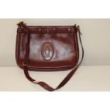 A Cartier oxblood leather shoulder bag. (signs of wear to the corners of the bag)