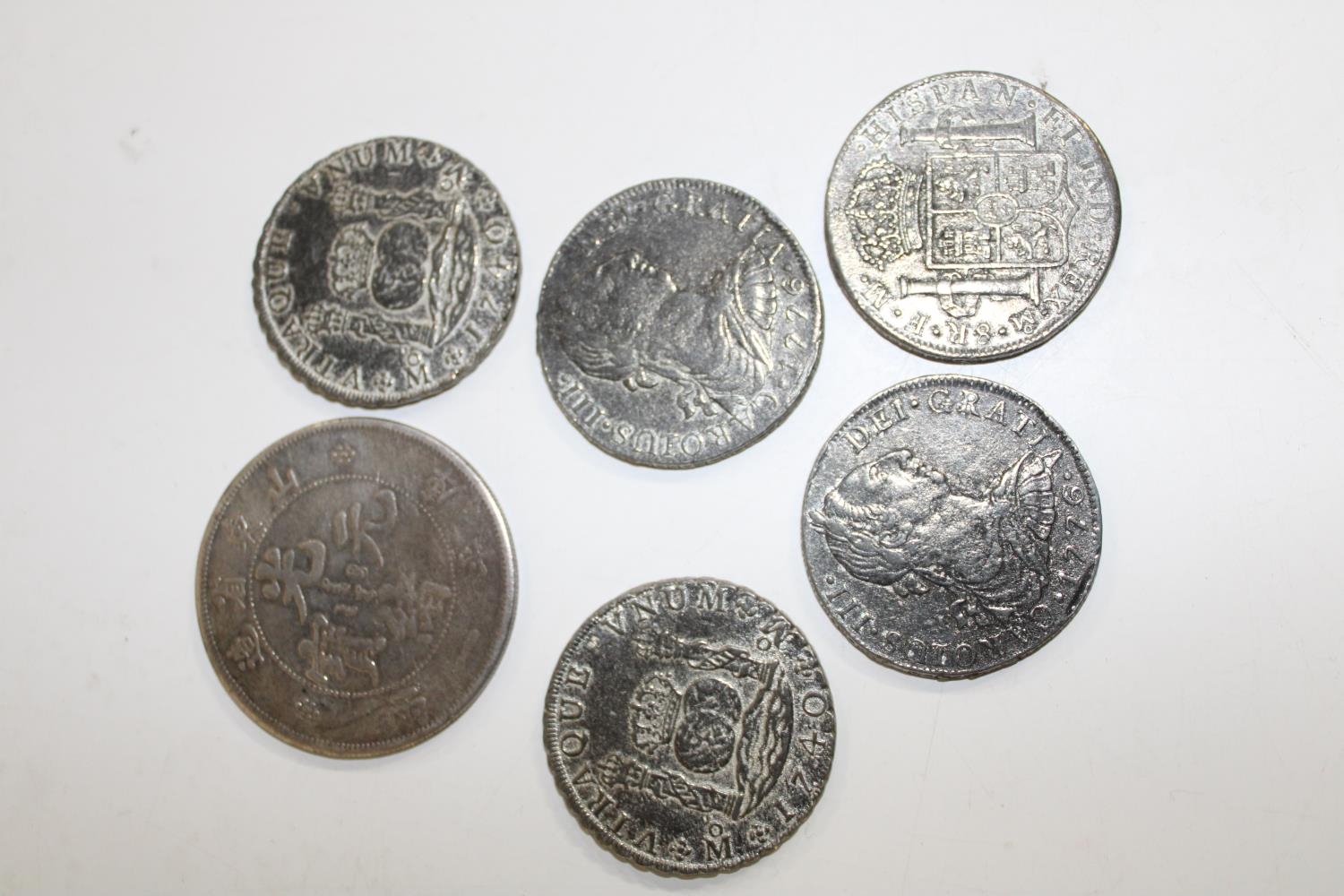 Five replica "pieces of eight" coins and a Chinese white metal coin