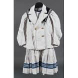 Mädchen-Matrosengarnitur: Kleid, Jacke, Plastron und Kragen. Baumwolle, weiß/blau besetzt.