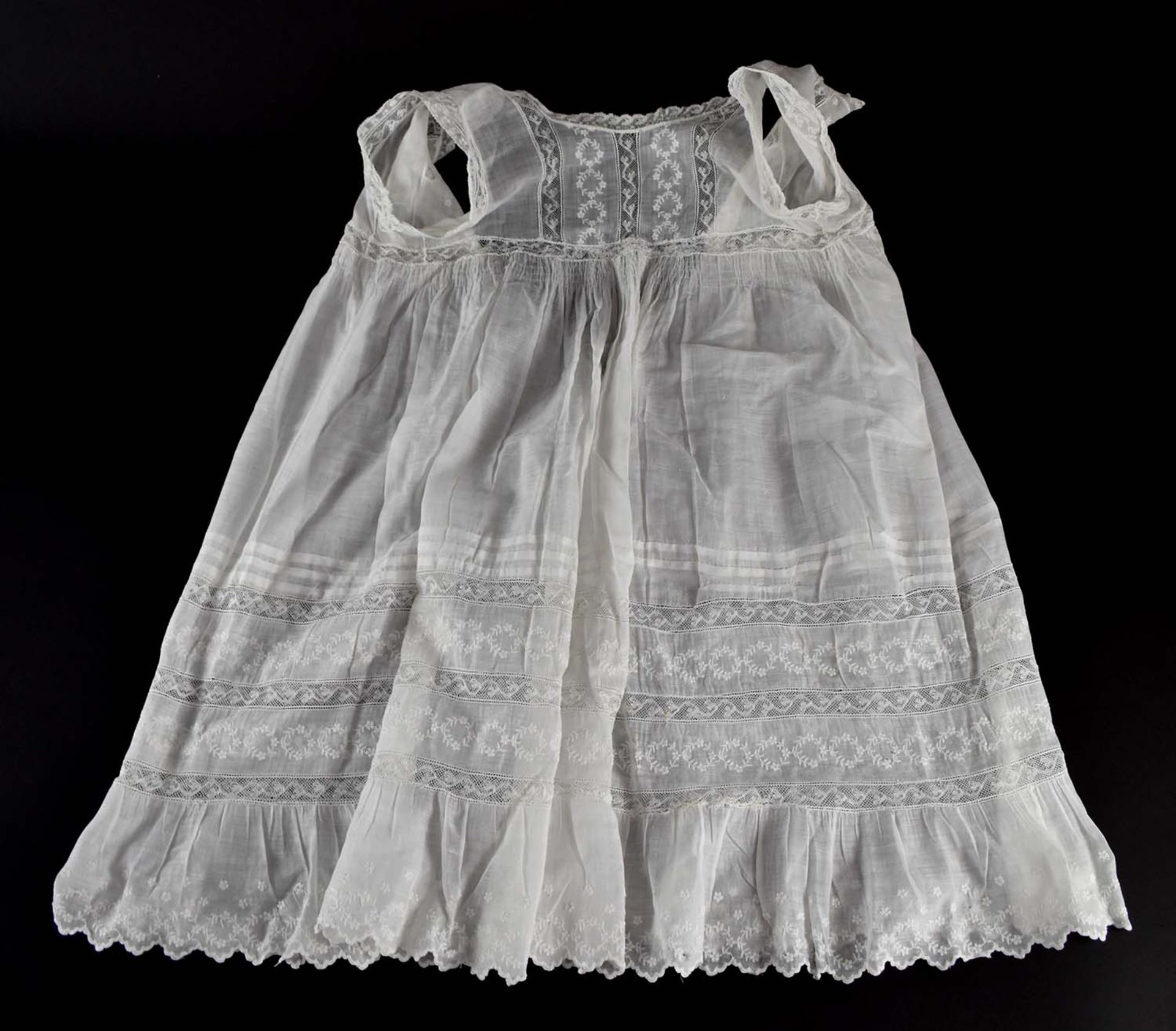 Kinderkleid. Feinster Batist, gesmokt, mit Spitzeneinsätzen und Biesen. Um 1900. H ca. 70 cm. Aus