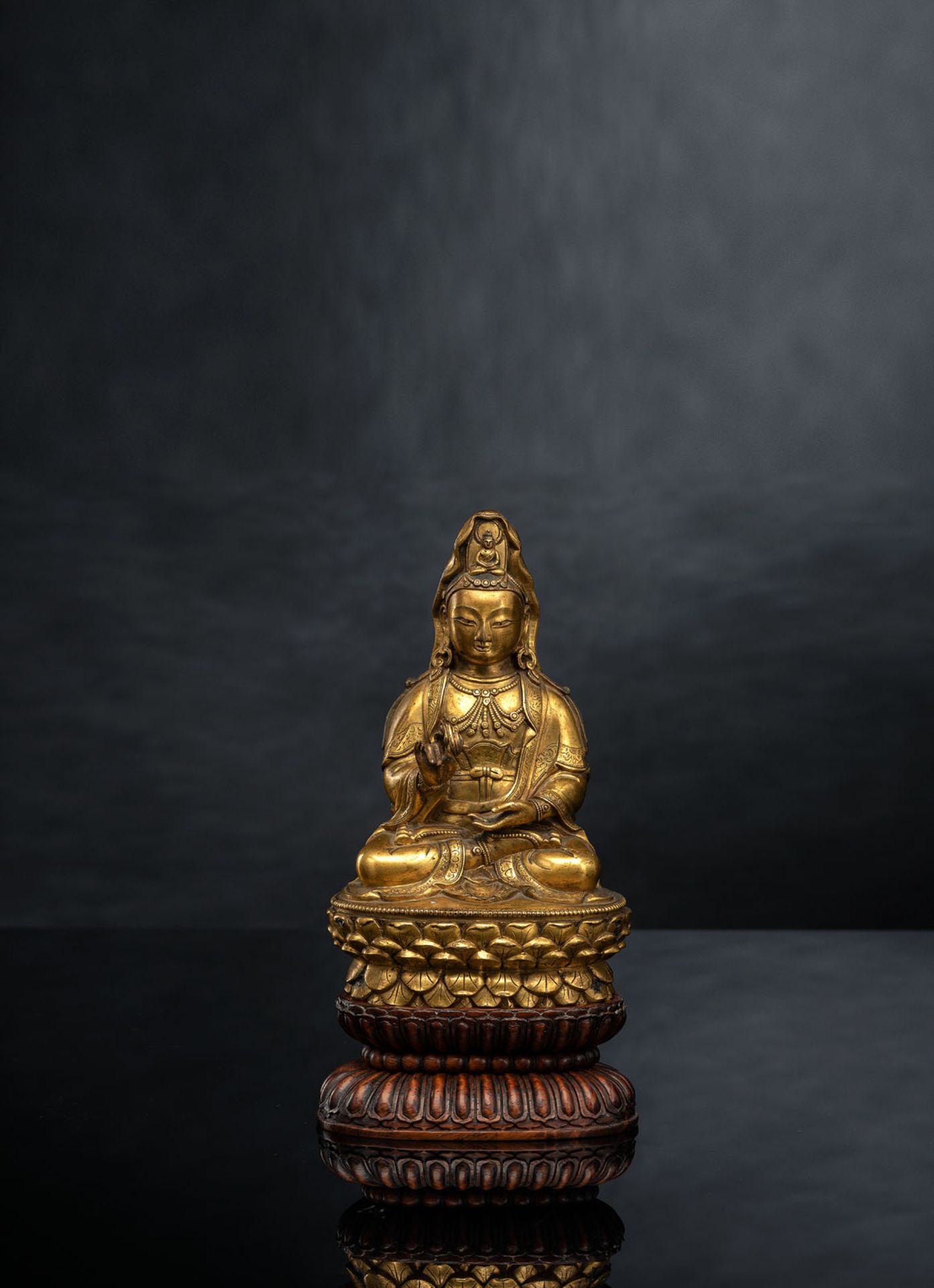 A FINE GILT-BRONZE FIGURE OF GUANYIN ON A LOTOS ABOVE A CARVED HARDWOOD LOTOS STAND