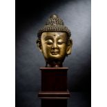 Großer feuervergoldeter Kopf des Buddha aus Bronze auf einem Holzstand
