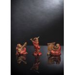 Gruppe von drei musizierenden Daruma aus Holz mit Lackdekor und Details in Horn und Elfenbein