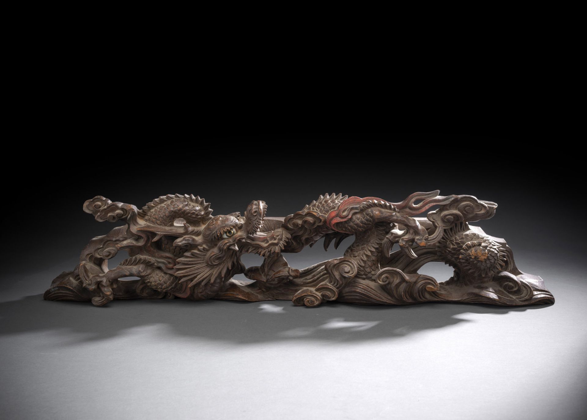 Zierleiste aus Holz mit geschnitztem Dekor eines sich windenden Drachens zwischen Gischt teils mit 