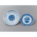 Zwei unterglasurblau dekorierte Teller aus Porzellan mit Blütenkorb bzw. Shou-Abstraktion
