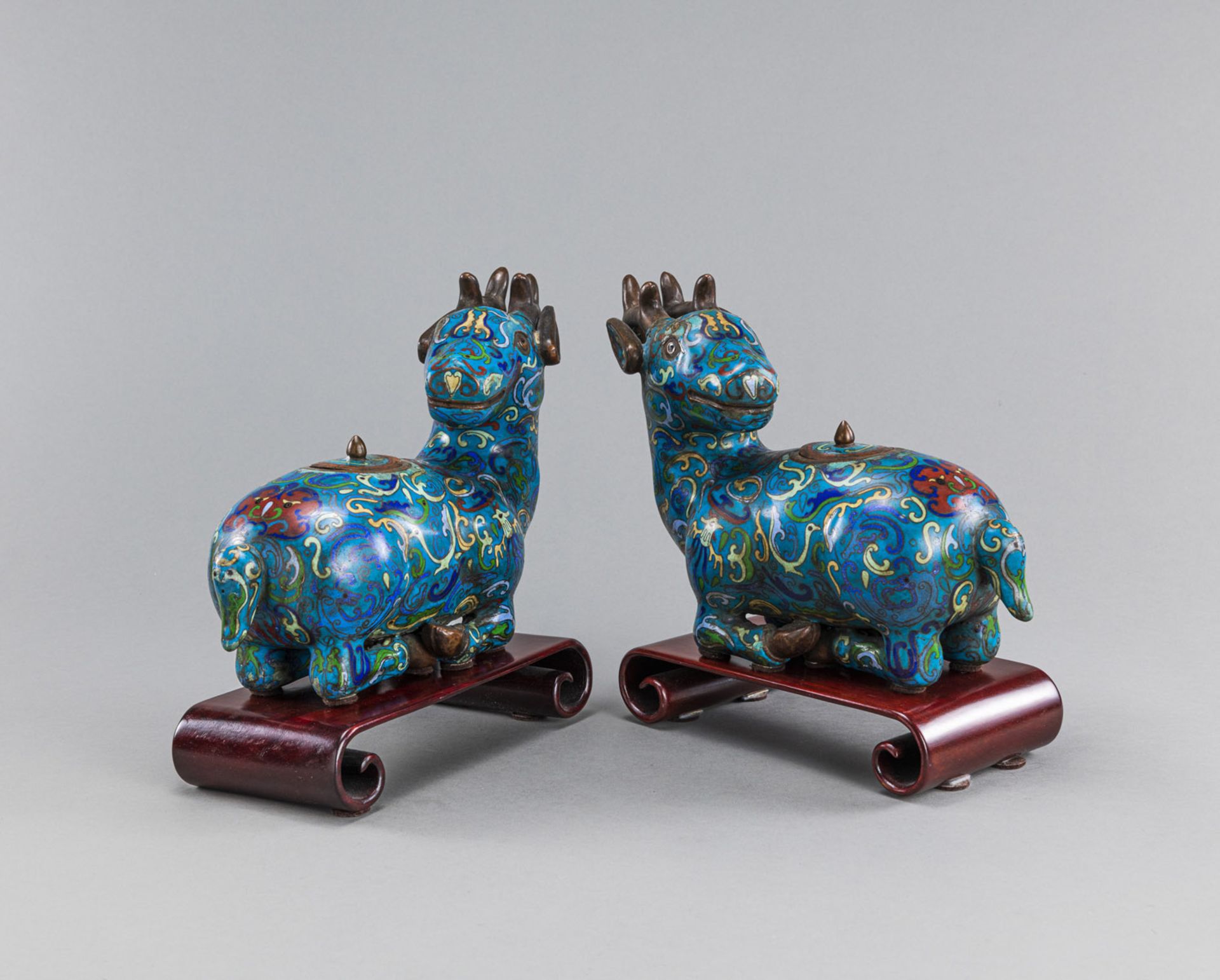 A PAIR OF CLOISONNÉ LIDDED VESSELS IN THE SHAPE OF LYING DEER ON A SEPARATE WOODEN BASE